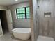 Elegant bathroom with soaking tub, tiled shower with a built-in shelf and a large window at 1516 Chase Ct, Riverdale, GA 30296