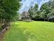 Expansive backyard with lush green grass, mature trees, a garden, and a swing set at 4114 Falcon Shores Nw Ct, Acworth, GA 30101