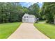 Charming white home featuring an attached three-car garage and a long, private driveway surrounded by lush greenery at 654 Cannon Rd, Sharpsburg, GA 30277