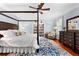 Large main bedroom has hardwood floors, four-poster bed, ceiling fan, bookshelf, and a blue and white rug at 654 Cannon Rd, Sharpsburg, GA 30277