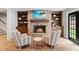 Cozy basement seating area with a stone fireplace, built-in shelves, and hardwood floors at 2430 Flat Stone Dr, Cumming, GA 30041