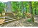 Exterior view of backyard steps leading to a wooded area and home's facade at 6520 Indian Acres Trl, Tucker, GA 30084