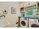 Well-organized laundry room with front-load washer, dryer, and open shelf storage at 6520 Indian Acres Trl, Tucker, GA 30084