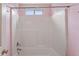 A clean, all-white tub shower with a window and a pink accent wall at 2667 Hampton Park Dr, Marietta, GA 30062