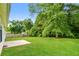 Spacious backyard featuring a concrete patio, large shade tree, and green lawn at 4895 Ozment Ridge Ct, Lithonia, GA 30038