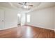 Spacious bedroom with tray ceiling, ceiling fan, wood-look floors, and ensuite bathroom entrance at 4895 Ozment Ridge Ct, Lithonia, GA 30038