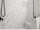 Close-up of a stylish shower area featuring marble tiling, a built-in bench, and sleek fixtures at 635 Opera Ln, Alpharetta, GA 30009