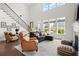 Cozy living room with large windows, comfortable seating, fireplace, and elegant staircase at 635 Opera Ln, Alpharetta, GA 30009