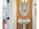 Charming powder room features exposed brick accent wall, pedestal sink, and decorative oval mirror at 1199 Huff Nw Rd # 112, Atlanta, GA 30318
