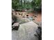 Cozy back patio with stone pavers, seating, and a charcoal grill surrounded by mature trees and landscaping at 3962 Fox Glen Dr, Woodstock, GA 30189