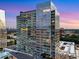 A high rise condominium with floor to ceiling windows overlooks a city skyline and sunset at 3325 Piedmont Rd Ne # 1907, Atlanta, GA 30305