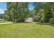 Large front yard with mature trees, green grass, and a home in the background at 408 Victoria Place Dr, Locust Grove, GA 30248
