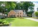 Inviting brick home boasts a lush green lawn and mature trees surrounding the property at 2192 Nine Oaks Nw Dr, Kennesaw, GA 30152