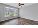 Bright bedroom featuring hardwood floors, a large window with blinds, and a ceiling fan; offering a clean and modern space at 217 Odyssey Turn, Conyers, GA 30012