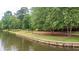 Scenic lake view with a stone retaining wall, lush trees, and a walking path, enhancing the natural setting at 434 Teal Ct, Roswell, GA 30076