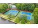 Aerial view of two fenced tennis courts next to a lake and wooded area, adding recreational appeal at 434 Teal Ct, Roswell, GA 30076