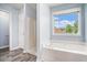 Bright bathroom with a large window and a white tiled shower and tub at 4438 Parmalee Path, Conley, GA 30288