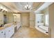 Bright bathroom with double sink vanity, a large mirror, travertine tile flooring, and a separate tub at 5284 Vernon Springs Nw Trl, Sandy Springs, GA 30327