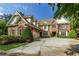 Stately brick home with stone accents, a manicured lawn, mature trees, and a spacious driveway with a two-car garage at 5284 Vernon Springs Nw Trl, Sandy Springs, GA 30327