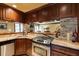 Bar and kitchenette featuring stone accents, wooden cabinets, stainless steel appliances, and granite countertops at 5284 Vernon Springs Nw Trl, Sandy Springs, GA 30327