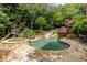 Backyard oasis with a stone-surrounded pool, waterslide, hot tub, and lush landscaping at 5284 Vernon Springs Nw Trl, Sandy Springs, GA 30327
