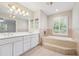 Bright bathroom with double vanity, soaking tub, and decorative tile at 2655 Nesbit Trl, Alpharetta, GA 30022