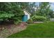 Backyard shed with a green door surrounded by lush trees and green grass at 2655 Nesbit Trl, Alpharetta, GA 30022