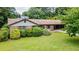 A well maintained front yard features mature trees, bushes, red brick, and a covered carport at 3854 Ridgewood Se Dr, Smyrna, GA 30080