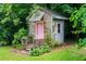 A charming shed in a lush backyard features a pink door, window, and a small covered porch at 3854 Ridgewood Se Dr, Smyrna, GA 30080