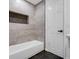 Nicely tiled bathroom featuring a white tub, a recessed storage cubby and dark floor tiles at 4800 Countryside E, Stone Mountain, GA 30083