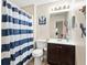 Bathroom features a vanity and toilet plus a shower with a blue and white striped curtain and wood flooring at 7720 Paddocks Mill Dr, Cumming, GA 30041