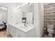 Bathroom features a double vanity, toilet, and view into the main bedroom plus decorative accent wall and wood flooring at 7720 Paddocks Mill Dr, Cumming, GA 30041