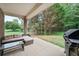 Covered outdoor patio with furniture and grill. Features a view of the large, grassy backyard with mature trees at 7720 Paddocks Mill Dr, Cumming, GA 30041