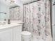 Bright bathroom with white fixtures, floral shower curtain, and a mirrored vanity at 620 Peachtree Ne St # 1001, Atlanta, GA 30308