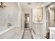 Luxurious bathroom showcasing a marble-tiled floor, soaking tub, and vanity with gold hardware at 3089 Marne Nw Dr, Atlanta, GA 30305