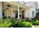 Inviting front porch featuring stylish fans, stone detailing, decorative shrubbery, and well-maintained landscaping at 2360 Whispering Nw Dr, Kennesaw, GA 30144