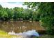 Picturesque pond surrounded by mature trees and lush foliage reflects the sky on a sunny day at 2360 Whispering Nw Dr, Kennesaw, GA 30144