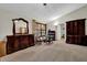 A carpeted bedroom with traditional wooden dressers and neutral walls, featuring a sitting area at 680 Spirit Falls Way, Johns Creek, GA 30022