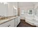 Bright bathroom features a double sink vanity with granite counters, a soaking tub, and wood look floors at 742 Maggie Nw Ct, Kennesaw, GA 30144