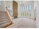 Open living room featuring a stone fireplace, high ceilings, and large windows, with staircase and carpeted floors at 5066 Healey Dr, Smyrna, GA 30082