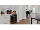 Bar area adjacent to the living room features a wine fridge, white cabinets, and gold hardware at 6640 Avis Walk, Alpharetta, GA 30005