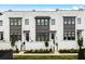 Stunning townhouse exterior with white brick, dark trim windows, and beautifully landscaped garden in a modern aesthetic at 6640 Avis Walk, Alpharetta, GA 30005