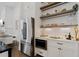 Modern kitchen with stainless steel refrigerator, open shelving, and sleek white cabinets for a minimalist feel at 6640 Avis Walk, Alpharetta, GA 30005