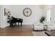 Elegant living room with hardwood floors, featuring a grand piano and sophisticated decor against a white brick accent wall at 6640 Avis Walk, Alpharetta, GA 30005