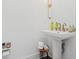 Simple powder room with pedestal sink and white walls with a gold light fixture at 6640 Avis Walk, Alpharetta, GA 30005