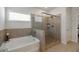 Bathroom featuring a separate soaking tub and glass enclosed shower with neutral tile at 7435 Ansley Park Way, Cumming, GA 30028