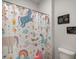 Bathroom showcases a shower with a playful unicorn shower curtain and charming wall art at 7435 Ansley Park Way, Cumming, GA 30028