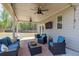 Outdoor living area with wicker furniture, blue cushions, ceiling fans, and a spacious backyard at 7435 Ansley Park Way, Cumming, GA 30028