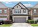 Charming brick townhome featuring a two-car garage, manicured lawn, and classic architectural details at 8215 Harlond Way, Suwanee, GA 30024