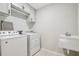 A clean laundry room with a white washer and dryer with grey accent tiles at 8215 Harlond Way, Suwanee, GA 30024
